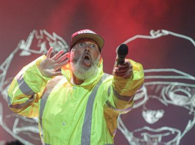 Vocalista do Limp Bizkit com uma mão na orelha e a outra segurando o microfone em direção ao público