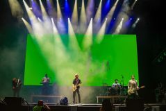 Palco com focos de luz no vocalista e cenário verde