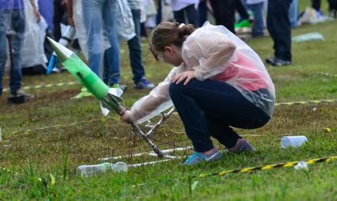 menina durante uma competição de astronomia com uma espécie de foguete