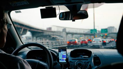 Motorista dirigindo em estrada acompanhando GPS no celular