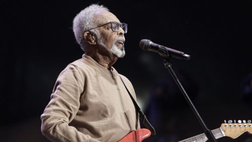 gilberto gil no palco tocando guitarra e cantando no microfone