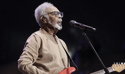 gilberto gil no palco tocando guitarra e cantando no microfone