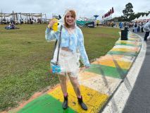 Jovem segura a capa de chuva ao lado do rosto enquanto posa com um copo na mão
