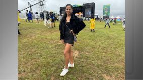 Mulher posa com a mão na cintura, bolsa pendurada e palco atrás
