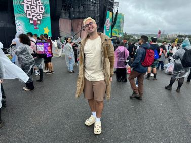 Homem de cabelo descolorido sorrindo em frente ao palco