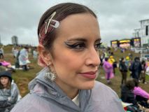 Mulher olhando para direita com meio-sorriso e maquiagem preta e azul