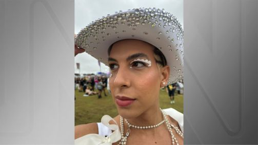 Jovem olhando para o lado e segurando chapéu estilo cowboy com maquiagem branca e pedrinhas