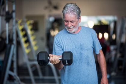 Homem idoso levantando um halter em exercício na academia