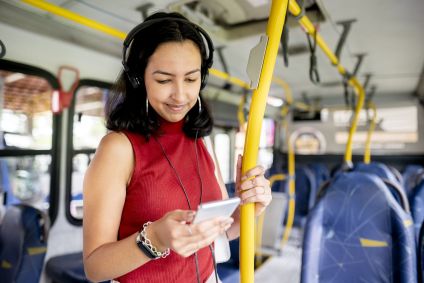 Mulher escuta música no celular enquanto pega o ônibus