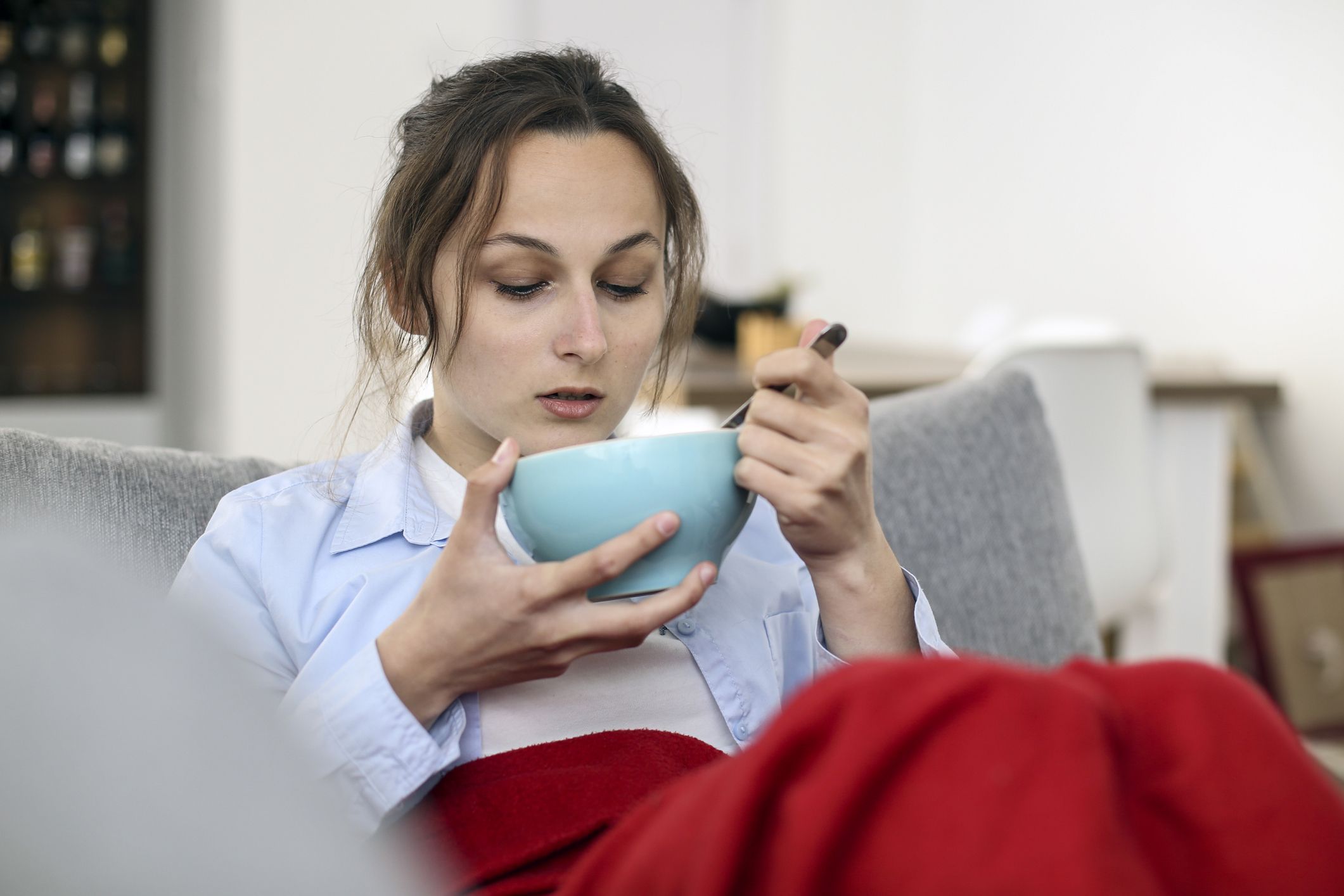 Mulher sentada no sofá tomando sopa