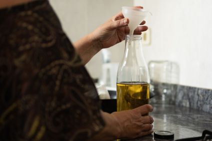 Mulher na cozinha em casa enchendo uma garrafa de vidro com azeite usado para cozinhar.conceito de reciclagem, desperdício zero na água e sustentabilidade e meio ambiente.