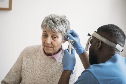 Idosa tendo o ouvido examinado por um médio otorrinolaringologista