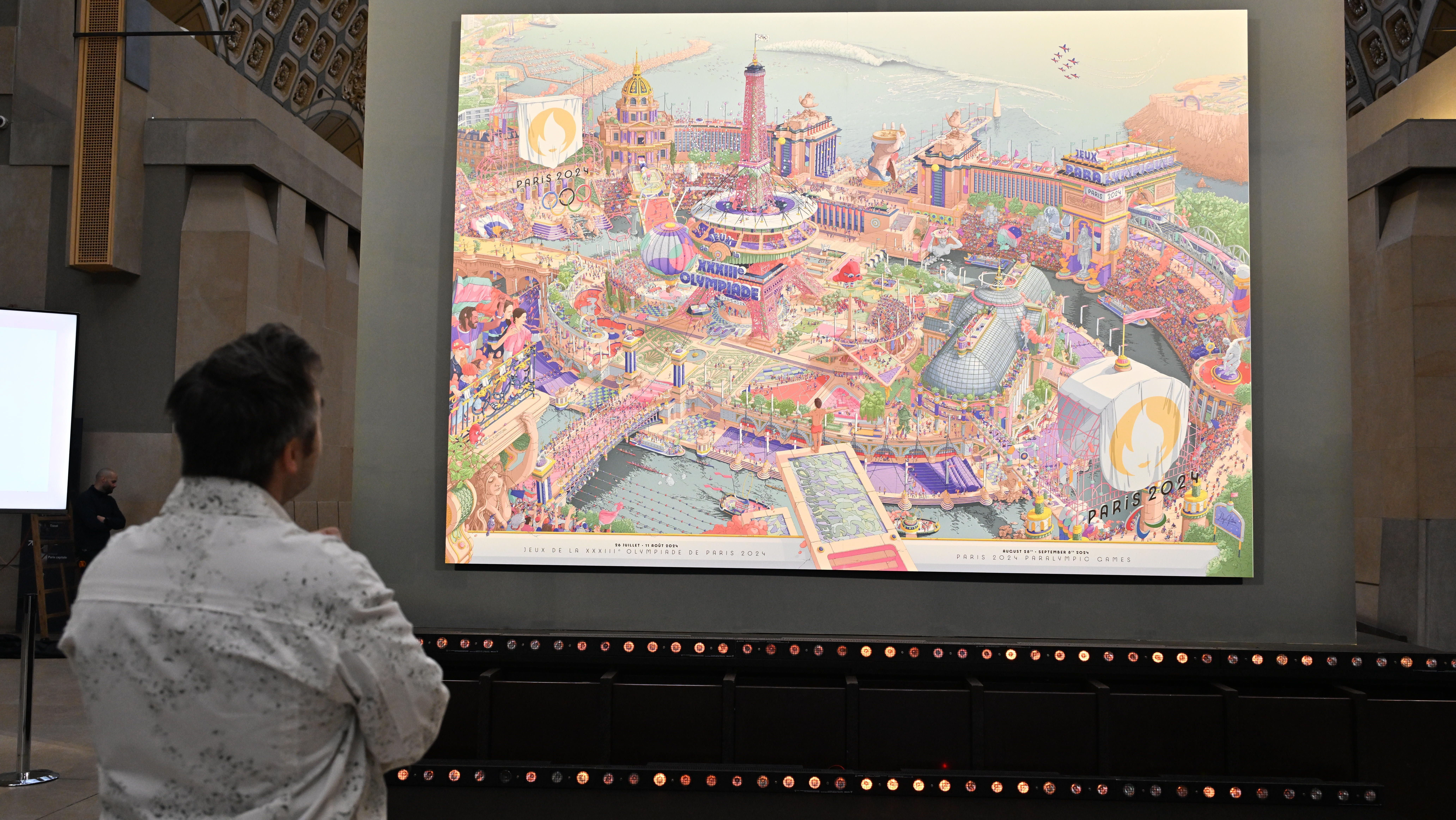 Ilustrador responsável pela obra, Ugo Gattoni observa os pôsteres de Paris 2024 / Mustafa Yalcin/Anadolu via Getty Images