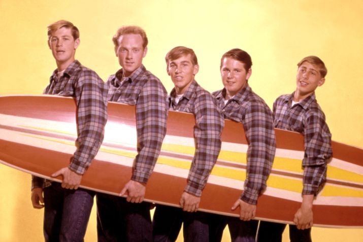 Os Beach Boys posam para um retrato com uma prancha de surf em 1962 • Michael Ochs Archives/Getty Images