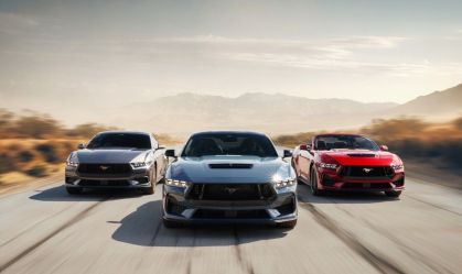 Trio de carros esportivos Ford Mustang, nas cores cinza, azul e vermelho, é visto na pista