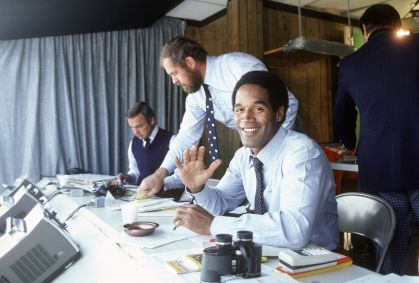 O.J. Simpson sorrindo para a câmera antes do início de um jogo de futebol americano da NFL por volta de 1980.