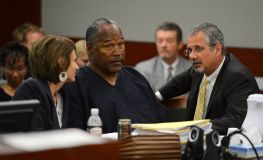 O.J. Simpson e seus advogados de defesa Patricia Palm (esq.) e Ozzie Fumo (dir.) conversam em uma audiência probatória no Tribunal Distrital do Condado de Clark em 17 de maio de 2013 em Las Vegas, Nevada.