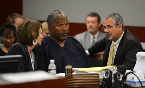 O.J. Simpson e seus advogados de defesa Patricia Palm (esq.) e Ozzie Fumo (dir.) conversam em uma audiência probatória no Tribunal Distrital do Condado de Clark em 17 de maio de 2013 em Las Vegas, Nevada.