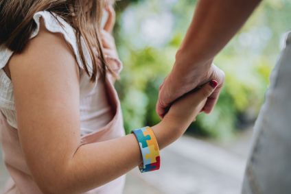 Criança autista de mãos dadas com a mãe