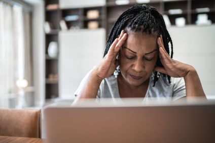 Mulher madura com dor de cabeça na frente do laptop em casa
