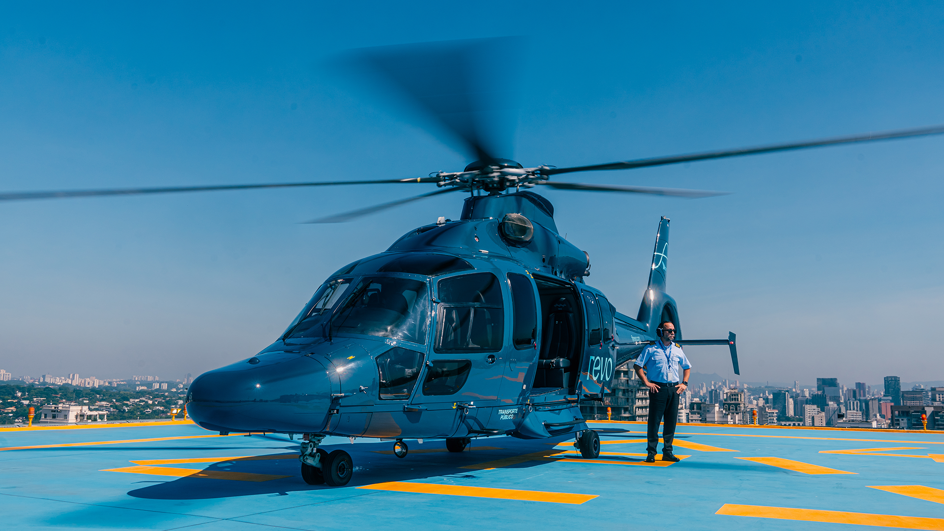 Homem pousando para foto ao lado de um helicóptero