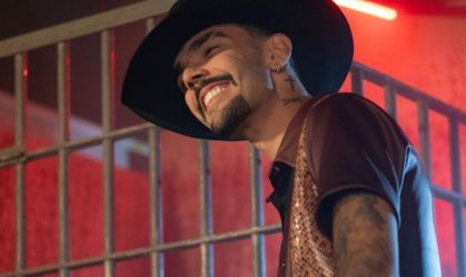 Cantor Luan Pereira usando um chapéu preto e sorrindo enquanto grava videoclipe de "Entra na Defender"