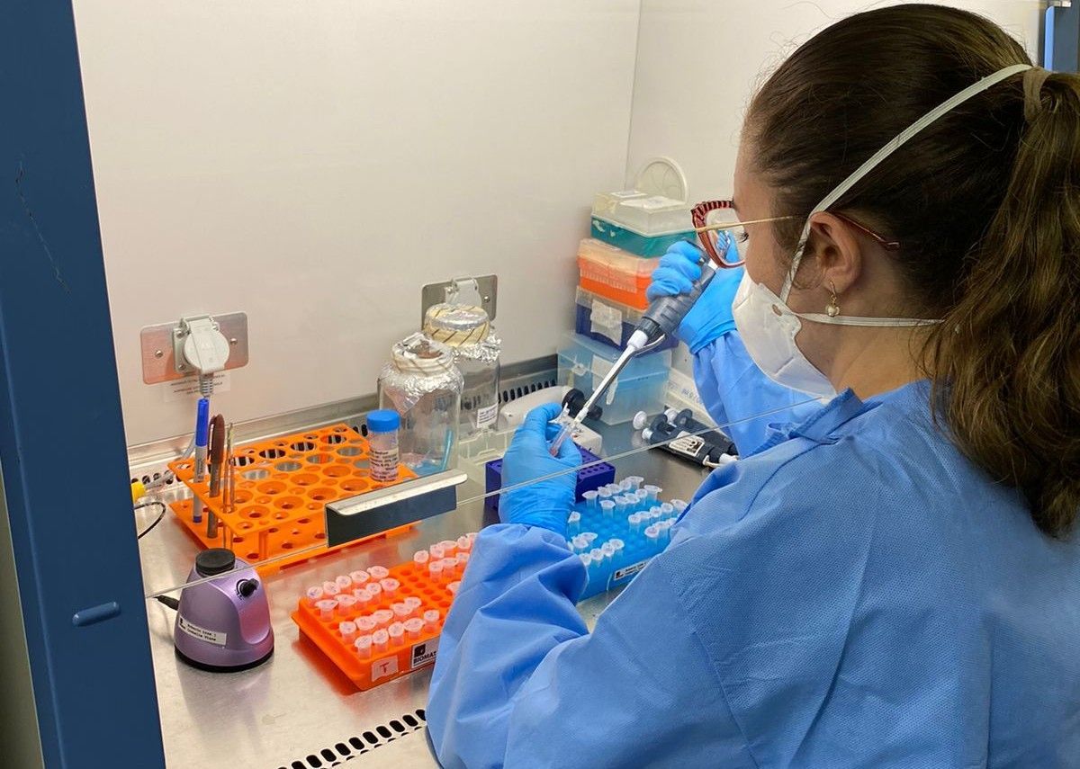 Pesquisadora vestindo EPI e máscara desenvolvendo vacina em laboratório