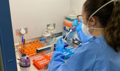 Pesquisadora vestindo EPI e máscara desenvolvendo vacina em laboratório