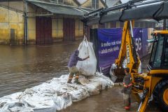 Equipe da prefeitura de Porto Alegre coloca sacos de areia em comportas para conter a água do Guaíba