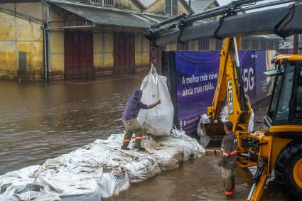 Equipe da prefeitura de Porto Alegre coloca sacos de areia em comportas para conter a água do Guaíba