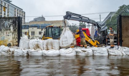 Equipe da prefeitura de Porto Alegre coloca sacos de areia em comportas para conter a água do Guaíba