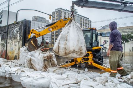 Equipe da prefeitura de Porto Alegre coloca sacos de areia em comportas para conter a água do Guaíba