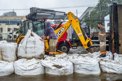Equipe da prefeitura de Porto Alegre coloca sacos de areia em comportas para conter a água do Guaíba