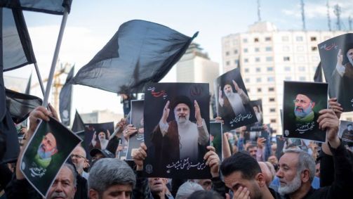 Homens iranianos seguram retratos do falecido presidente Ebrahim Raisi, que morreu em um acidente de helicóptero no nordeste do Irã