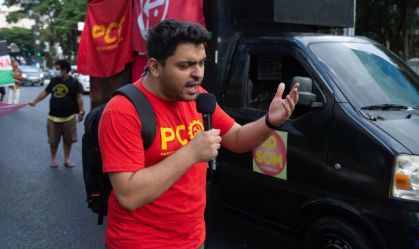 Foto mostra João Pimenta com uma camisa vermelha discursando na rua próximo a um caminhão