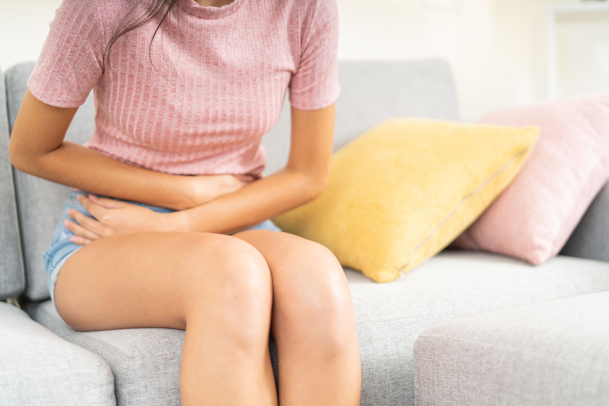 Young woman sitting holding her lower belly for menstrual cramps
