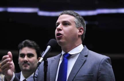 Imagem mostra o ex-deputado Arhur Bisneto discursando. Ele veste um terno cinza, grava azul e está com a mão levantada.