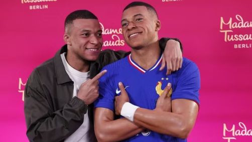 Kylian Mbappé ao lado de sua nova estátua