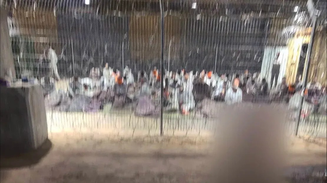 Uma fotografia vazada de um recinto onde detidos em agasalhos cinza são vistos com os olhos vendados e sentados em colchões finos como papel. A CNN conseguiu geolocalizar o hangar nas instalações de Sde Teiman. Uma parte desta imagem foi desfocada pela CNN para proteger a identidade da fonte / CNN
