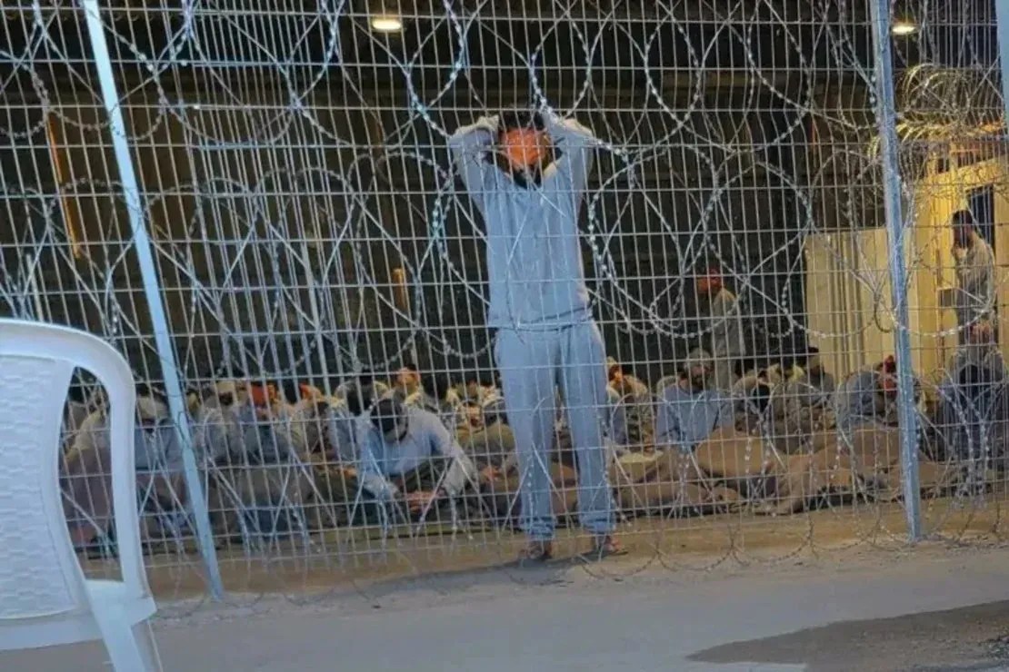 Uma fotografia vazada do centro de detenção Sde Teiman, em Israel, mostra um homem vendado e com os braços acima da cabeça / CNN
