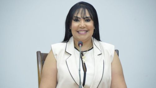 Janad Valcari é branca e tem cabelo preto e liso. Usa roupa branca e sorri.