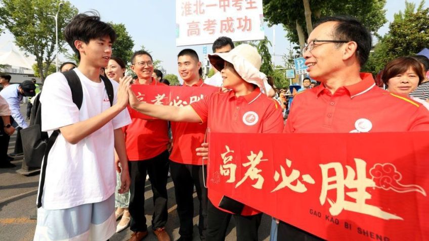Aluno cumprimenta professores antes de entrar em local do Exame Nacional de Admissão à Faculdade de 2024 (também conhecido como Gaokao) em 7 de junho de 2024 em Huaibei, província de Anhui, na China / Li Xin/VCG via Getty Images
