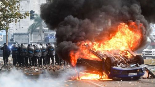 Carro pega fogo em frente ao Congresso durante um protesto contra o plano de reforma do governo do presidente Milei, que está sendo debatido no Congresso da Argentina