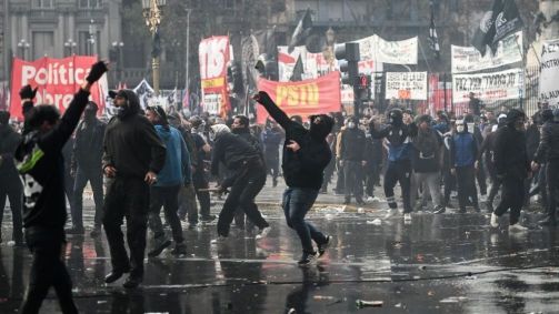 Manifestantes jogam objetos em direção ao prédio do Congresso durante um protesto contra o megaprojeto de lei do governo ultraliberal do presidente Milei que está sendo debatido no Congresso da Argentina