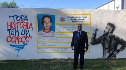 Tio de Neymar, José Benicio, em frente ao muro com a carteirinha do sobrinho, Neymar, na época em que estudou no colégio