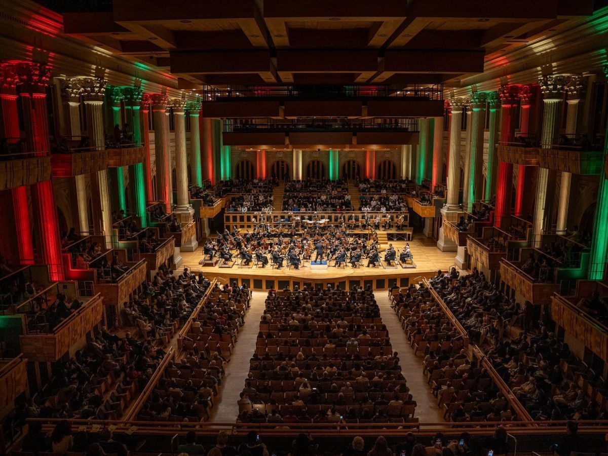 Orquestra sinfônica executando trilha sonora clássica de cinema com regente e instrumentos de cordas