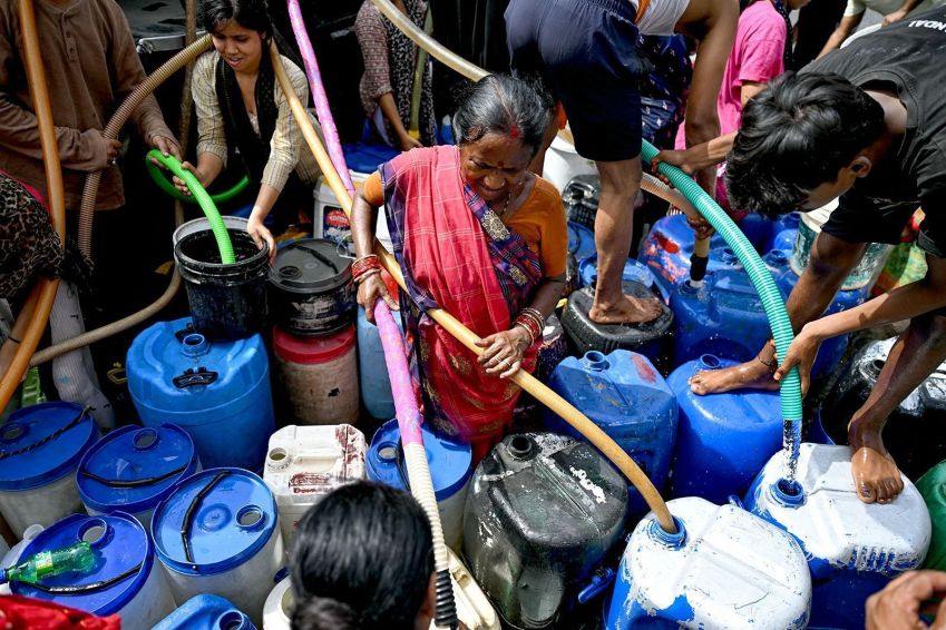 Moradores enchem seus recipientes com água fornecida por um caminhão-tanque municipal em Nova Délhi, no dia 19 de junho. / Money Sharma/AFP/Getty Images via CNN Newsource