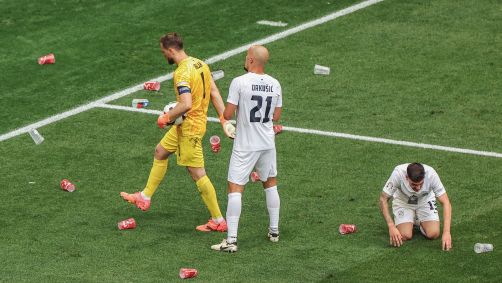 Jogadores da Eslovênia recolhem copos do campo durante jogo da Eurocopa