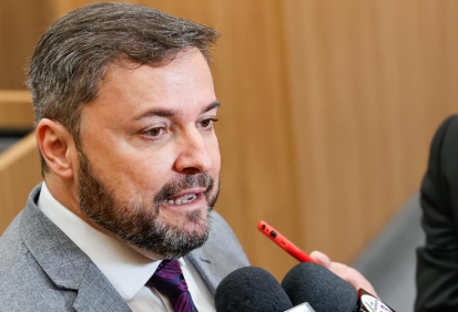 Fábio Novo é branco, tem cabelo e barba grisalhos. Usa terno cinza.
