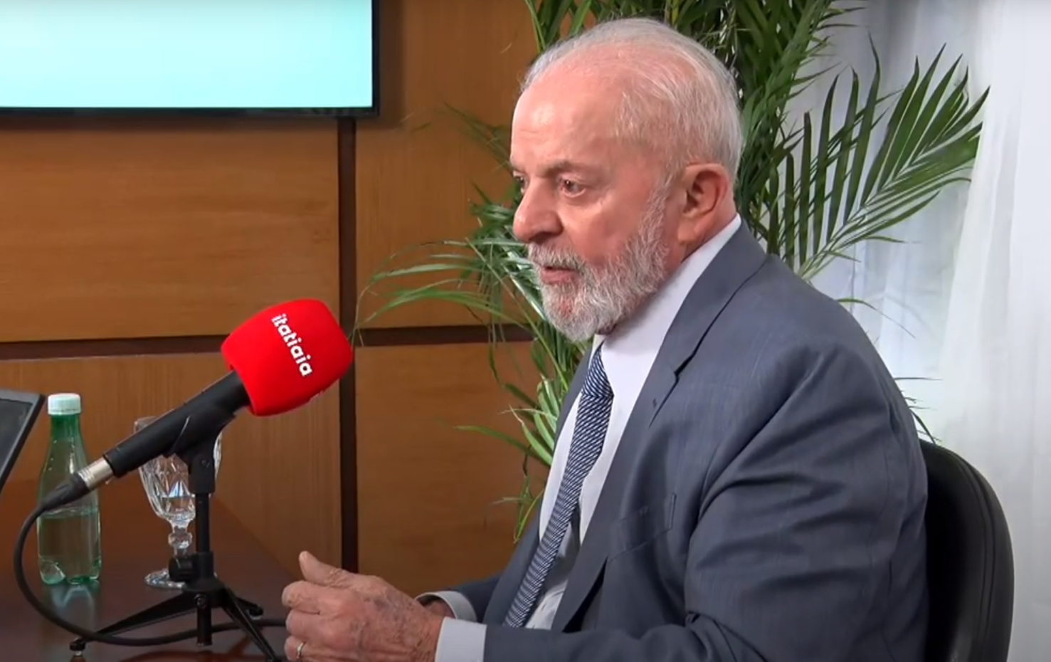 Foto mostra o presidente Lula. É idoso, branco, veste um terno cinza, camiseta branca e gravata.